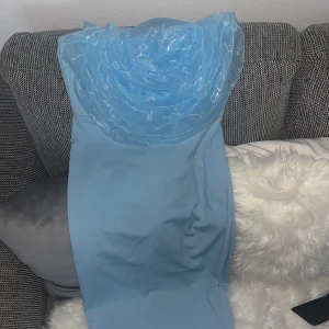 Ljusblå axelbandslös klänning från SHEIN - Säljer en ljusblå axelbandslös klänning från SHEIN med unik draperad detalj upptill. Klänningen har en figurnära passform och är perfekt för dig som vill sticka ut med en modern look.