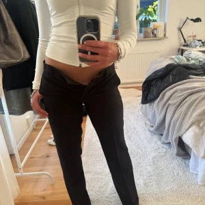 Svarta kostymbyxor med låg midja - Säljer ett par svarta kostymbyxor med låg midja och raka ben. Helt oanvända med prislapp kvar på. 