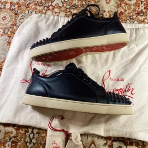 Mörkblå sneakers med nitar från Christian Louboutin - Tjena!🙌🏻 Säljer ett par mörkblå sneakers från Christian Louboutin med coola svarta nitar på tån. Skorna har vit sula och klassisk snörning. Perfekta för dig som vill sticka ut med en edgy och lyxig stil. Skorna är äkta! Vill bli av med skorna då dom inte passar och bara ligger så Priset kan ändras, byte är intressant! 