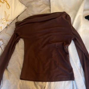 Brun one shoulder topp från Nelly - Säljer en brun långärmad topp med one shoulder-design från Nelly