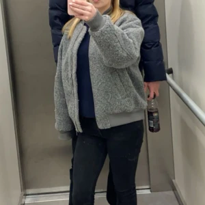 Grå teddyjacka med dragkedja - Mysig grå teddyjacka med dragkedja framtill och ribbade muddar. Jackan har fickor på sidorna och en extra ficka med dragkedja på ena ärmen. Perfekt för kyligare dagar och ger en avslappnad look. Nästan helt ny, använd ca 2 ggr💗 pris kan diskuteras