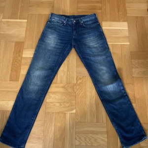Blå jeans från Emporio Armani - Säljer ett par klassiska blå jeans från Emporio Armani med raka ben. Jeansen har fem fickor, normal passform och logotyp på bakfickan. Perfekta för dig som gillar stilrena och tidlösa jeans.