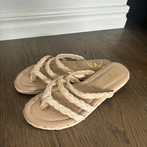 Supersnygga sandaler till sommaren! - Säljer ett par snygga beige sandaler från Zara med flätade remmar och platt sula. Perfekta för sommaren. Storlek 41 men passar 40. Helt oanvända. Pris går att diskutera!