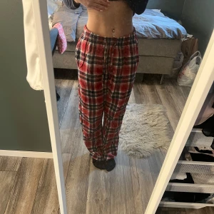 Röda rutiga mjukisbyxor - Säljer ett par röda och blåa rutiga mjukisbyxor med resår i midjan och avslappnad passform. Perfekta för att chilla hemma eller mysa runt i. Byxorna har en klassisk rutig design och är superbekväma.