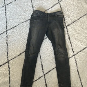 Svarta skinny jeans från Jack & Jones - Säljer ett par svarta slim jeans från Jack & Jones, modell Liam. Klassisk femficksdesign med dragkedja och knapp i midjan. Snygg passform som sitter bra hela vägen ner. Passar dig som är runt 172. 27/30 Små tecken på användning med små original slitningar.