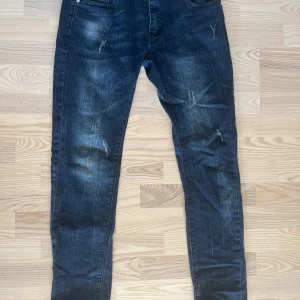 Mörkblå jeans från Ross Kemp - Snygga mörkblå jeans från Ross Kemp med slitningar på benen för en trendig look. Klassisk femficksmodell med knapp och dragkedja i gylfen. Perfekta till vardags för en avslappnad stil.