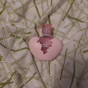 Ariana Grande parfym i hjärtformad flaska - Säljer en söt parfym från Ariana Grande i en ljusrosa hjärtformad flaska med ett sprucket hjärtdesign och rosa transparent kork. Perfekt för dig som gillar unika och lekfulla flaskor.