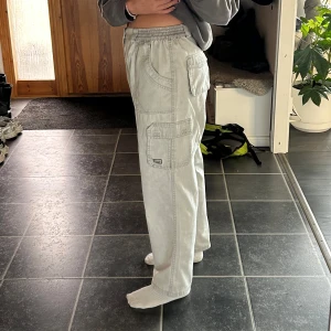 Ljusgrå cargopants med resårmidja - Säljer ett par ljusgrå cargopants med resår i midjan och flera stora fickor på sidorna. Byxorna har en avslappnad passform och är perfekta för en chill vardagsstil. Passar dig som gillar loose fit🤩Storlek L och sitter oversize på mig som är M.