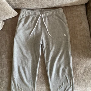Grå mjukisbyxor från Champion - Säljer ett par grå mjukisbyxor från Champion i storlek medium. Byxorna har resår i midjan med vit snörning och är i stort sätt aldrig använda. Perfekt skick! Hör av er vid prisförslag😊