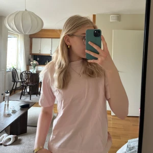 Ljusrosa t-shirt - En basic ljusrosa t-shirt med rund halsringning och korta ärmar. Perfekt för en enkel och avslappnad stil. T-shirten har en rak passform och är tillverkad i ett mjukt material.