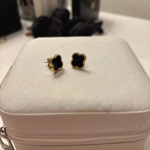 Klöver örhängen svart/guld - Använda 3 gånger endast. Fast pris 150kr. Inköpta 399kr. Jag kommer ej skicka med plupparna man stänger pga hygiens skäl. Det är vanliga pluppar som kommer med varje örhängen som man kan ta från sin egna.