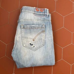 Ljusblå Dondup jeans - Säljer ett par ljusblå jeans från Dondup med slitningar och broderade detaljer på bakfickorna. Jeansen har raka ben och klassisk femficksdesign. Perfekta för en avslappnad och trendig look. Priset kan diskuteras!😎