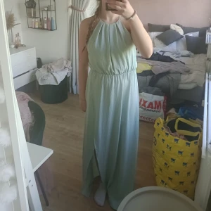 Ljusblå balklänning/ långklänning med spets och öppen rygg - Ljusblå balklänning/ långklänning med halterneck och öppen rygg. Klänningen har spetsdetaljer på ryggen och en slits framtill.Väldigt fint skick då en inte är så mycket använd. Från Gina Tricot men saknar storlek men jag skulle säga S. 