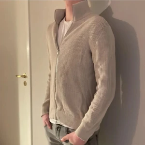 Beige cardigan från East West  - Hej! Säljer min  beige cardigan från EAST WEST i storlek M. Har använt den ett väldigt fåtal gånger, som nytt! Tar inga bud.