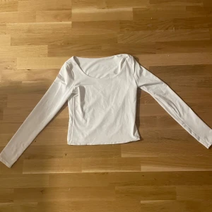 Vit långärmad topp med rund hals - Säljer en enkel och stilren vit långärmad topp med rundad halsringning. Toppen är i ett mjukt och stretchigt material som sitter skönt på kroppen. Perfekt att matcha med jeans eller kjol för en clean look.