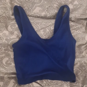 Blå ribbad linnetopp från SHEIN - Säljer en blå ribbad linnetopp från SHEIN. Toppen har breda axelband och v-ringad halsringning. Perfekt för varma dagar och enkel att matcha med olika outfits.