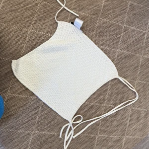Vit stickad croppad linnetopp - Säljer en vit stickad croppad topp med tunna knytband i sidorna. Perfekt för varma dagar och enkel att styla med jeans eller kjol. Supersnygg och trendig modell!🌸🌸