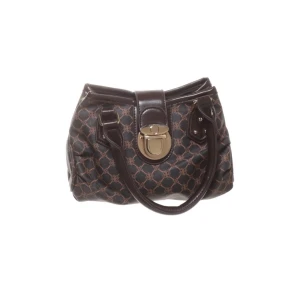 Mörkbrun mönstrad handväska från Missguided - Säljer en snygg mörkbrun handväska från Missguided med klassiskt mönster och stora handtag. Väskan har ett stort spänne i metall framtill och detaljer i skinn. Perfekt för dig som vill ha en stilren accessoar. 