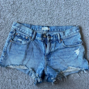 Blå jeansshorts från Gina Tricot - Snygga blå jeansshorts från perfekt jeans från Gina Tricot med fransiga kanter och slitna detaljer. Perfekta för sommaren! Använda ett fåtal gånger!🥰
