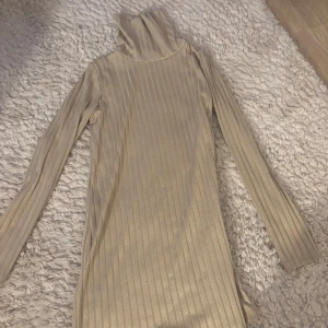 Beige ribbad tröj/klänning - Snygg beige ribbad klänning med polokrage och långa ärmar. Perfekt för kyligare dagar med sin stilrena design och bekväma passform. Ett måste i garderoben för en chic look.