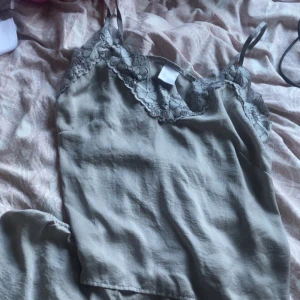 Grått pyjamas sett  - Fint pyjamas sett med spets detaljer på både shortsen och linnet. Jätteskönt material som passat perfekt till en mys kväll eller att sova i.