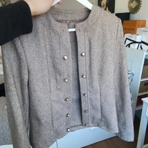 Beige kavaj från Shein - Snygg beige kavaj från Shein med ett klassiskt fiskbensmönster. Kavajen har långa ärmar och knäpps med stilrena knappar framtill. Perfekt för en chic och elegant look.
