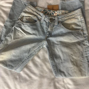 Lågmidjade jeans från Replay - Snygga ljusblå jeans från Replay med snygga detaljer på bakfickan och en unik patch med pärlor och stenar. Jeansen är i storlek 30 🌸köpta från Sellpy men för stora för mig. 