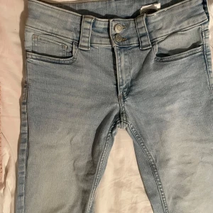 Ljusblå low waist jeans med bootcut - Snygga ljusblå jeans med bootcut. De har en dragkedja och knapp framtill samt dekorativa bakfickor med knappdetaljer.