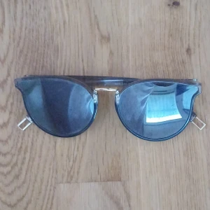 Svarta solglasögon med transparenta skalmar - Snygga svarta solglasögon med transparenta skalmar och en cool guldnäsa. Perfekta för en stilren look. Passar både till stranden och stan.