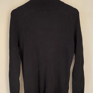 Turtle neck tröja H&M - Säljer en svart ribbad tröja från H&M i muscle fit. Tröjan har långa ärmar och en stilren design som passar perfekt för en modern look. Sparsamt använt, i gott skick.