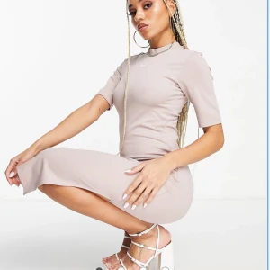 Nike figursydd klänning (ny) greige  - SÅ fin, vårig klänning i mer robust material & sitter helt otroligt på, väldigt smickrande för figuren.  ”Halvhög” krage, logga på bröstet. Får säljas då detta inte var min färg tyvärr. Skulle säga att den är greige (brungrå)