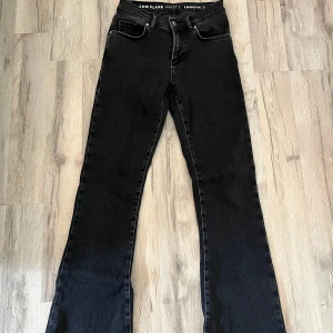 Svarta bootcut jeans - Snygga svarta bootcut jeans med låg midja. Perfekta för en stilren look. De har en klassisk design med dragkedja och knapp framtill.