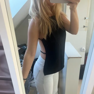 Svart ärmlös topp med öppen rygg - Snygg svart ärmlös topp med öppen rygg och smala axelband. 