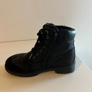 Svarta boots med snörning och dragkedja - Snygga svarta boots med både snörning och dragkedja för enkel på- och avtagning. De har en robust sula och är fodrade för extra värme. Perfekta för kyligare dagar.