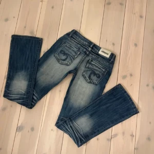Blå jeans från New  Denim - Snygga blå jeans med slitna detaljer från New Denim. De har en klassisk femficksdesign och en knappgylf. Perfekta för en avslappnad stil.