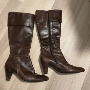 Bruna stövlar från Ecco - Snygga bruna stövlar från Ecco i skinn med dragkedja på sidan. Köpta begagnat men i väldigt fint skick. Säljer då jag tyvärr inte fick igen dragkedjan då dem va lite för små för mina vader. Lite slitningar som ni ser på bilderna men annars fint skick. Skriv för frågor eller mer info!