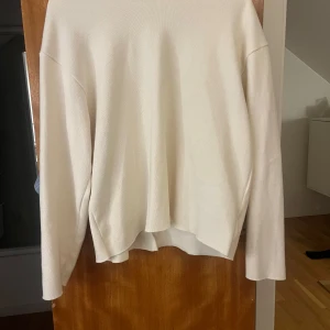 Vit stickad tröja - Säljer en stilren vit stickad tröja med lång ärm. Perfekt för kyligare dagar och enkel att matcha med olika outfits. Tröjan har en klassisk design utan extra detaljer.
