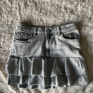 Grå jeanskjol med volang - En grå jeanskjol med volanger. Jag har sytt den själv. Helt oanvänd. Man kan välja om man vill ha den lågmifjad eller hög eller mid😊