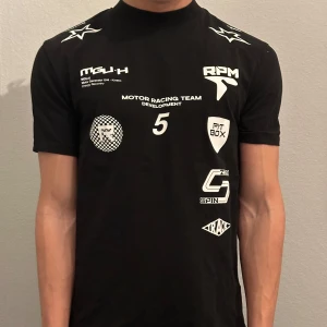 Svart t-shirt med racingtryck - Skön oanvänd Tisha med ”racing tryck”! Passar perfekt till sportiga tillfällen! Killen på bilden e 180, o väger 65 kg! Sitter något tajt! 