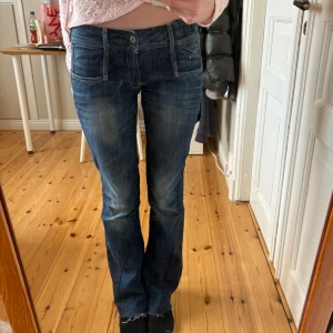 Mörkblå jeans från GS - Snygga mörkblå jeans från GS med en klassisk femficksdesign. De har en låg midja och en bootcut-stil som ger en avslappnad look. Perfekta för en casual outfit. De är utsydda på sidan och passar mig som brukar ha 25/32.