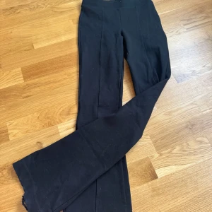 Svarta kostymbyxor - Snygga svarta kostymbyxor som är bootcut-stil. Byxorna har en stilren design med diskreta bakfickor. Perfekta för en elegant look.