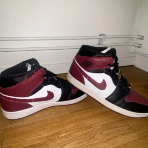 Nike Air Jordans i vinrött och svart - Snygga Nike Air Jordans i en stilren kombination av vinrött, svart och vitt. Skorna har klassisk snörning och en ikonisk design som passar perfekt för sneakerheads. Perfekta för att lyfta din stil till nästa nivå.