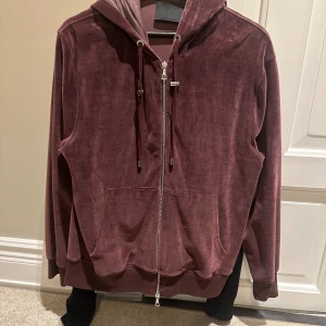 Vinröd hoodie från Limitato - Säljer en OG snygg vinröd hoodie från Limitato i mjukt sammetstyg. Tröjan har en dragkedja framtill och en unik design med ett konstverk på ryggen. Perfekt för dig som vill ha något annorlunda och stilrent. Hör av dig vid intresse! nypris 4599kr. Pris kan förhandlas!!!Box ingår