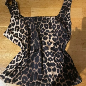 Leopardmönstrad linne - Snygg leopardmönstrad linne med breda axelband. Perfekt för en djärv och trendig look. Materialet är mjukt och bekvämt, vilket gör den idealisk för både vardag och festliga tillfällen.