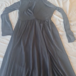 Svart långklänning från Nly One - Elegant svart långklänning från Nly One med långa ärmar och v-ringad design. Perfekt för en stilren look.