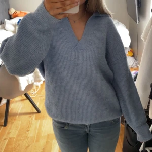 Blå stickad tröja från mango - Säljer en mysig ljusblå stickad tröja från mango. Tröjan har en v-ringad krage och långa ärmar, perfekt för kyliga dagar. Tjockt stickat material. Kan ändra till lägre pris.  
