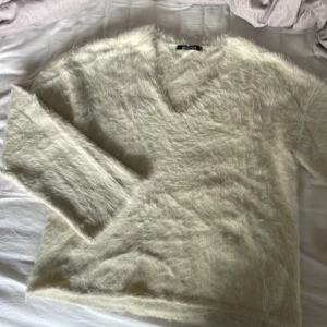Vit fluffig tröja från Gina Tricot - Säljer en supermjuk och fluffig vit tröja från Gina Tricot. Den har en v-ringad hals och långa ärmar, perfekt för att hålla sig varm och stilren. Passar perfekt för kyliga dagar. 🧥✨