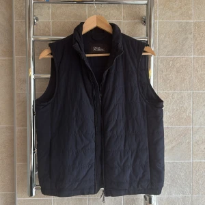 Marinblå väst från Oscar Jacobson - Snygg svart väst från Oscar Jacobson med dragkedja framtill. Perfekt för lager-på-lager under kyligare dagar. Västen har en stilren design med praktiska innerfickor.