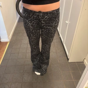 Svarta bootcut jeans med leopardmönster - Säljer ett par svarta jeans med grått leopardmönster och bootcut passform. M men skulle säga passar S bättre. Omsydda till lågmidjade.