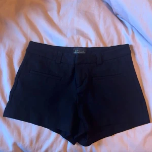 Svarta shorts från Bershka - Snygga svarta shorts från Bershka med kostymdesign. De har hällor för bälte och diskreta fickor både fram och baktill. Perfekta för en clean och stilren look. Oanvända!